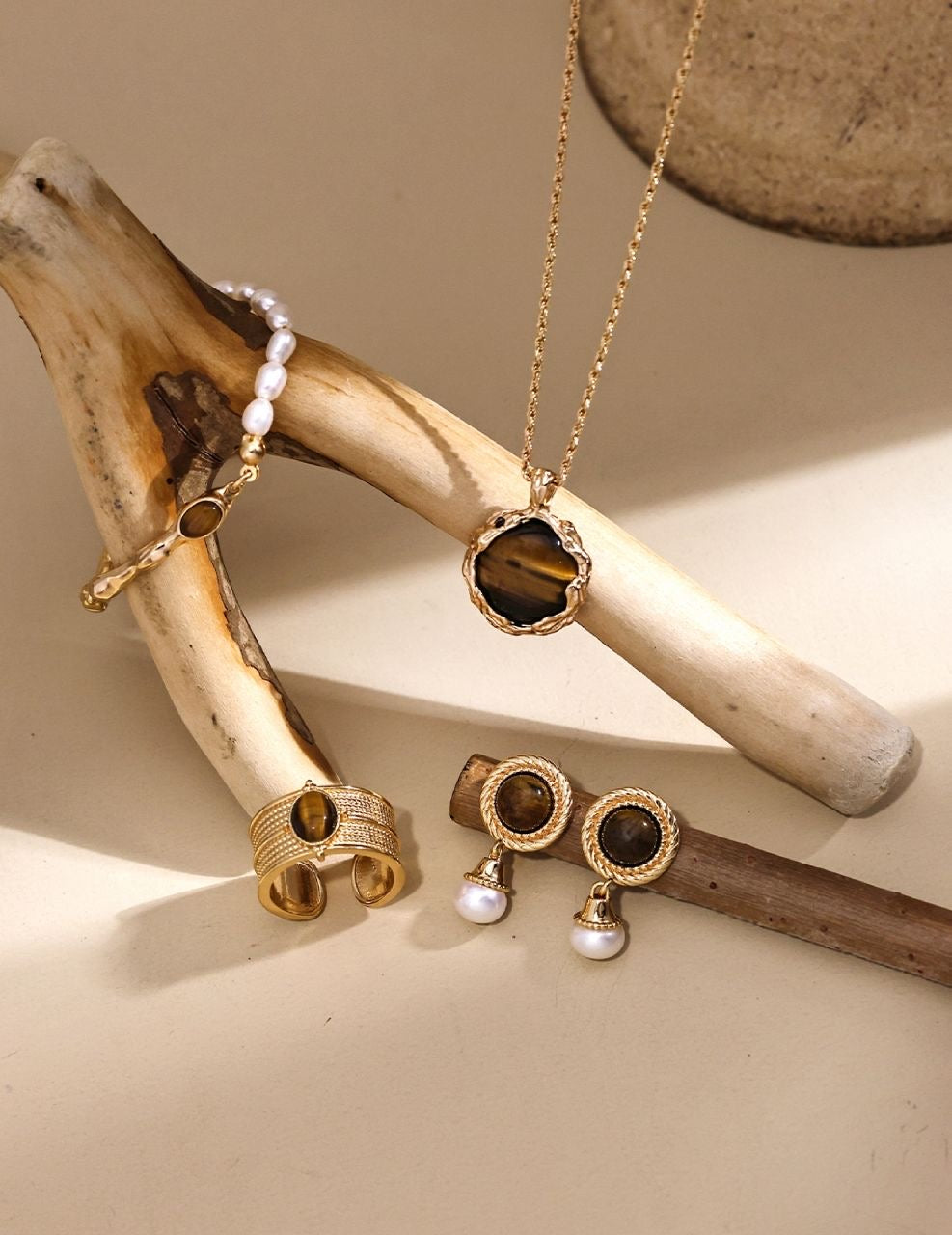 a set of tiger's eye stone jewelry placed on wood stick