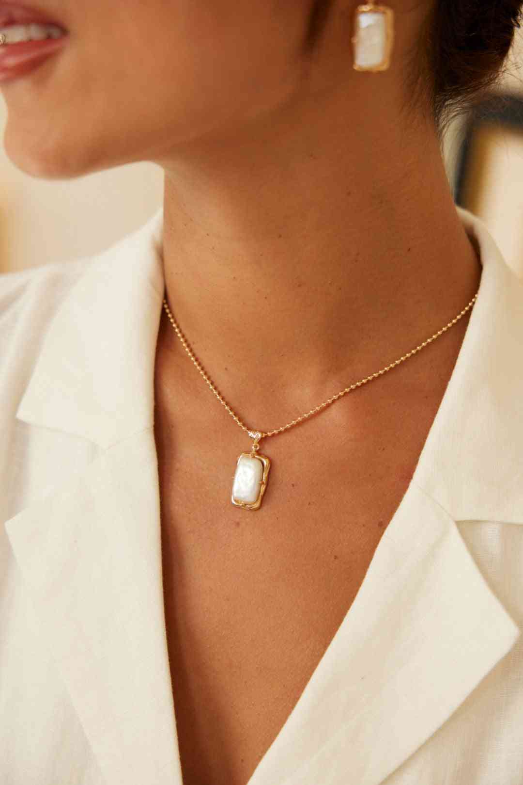 Gold pearl necklace worn with white blouse