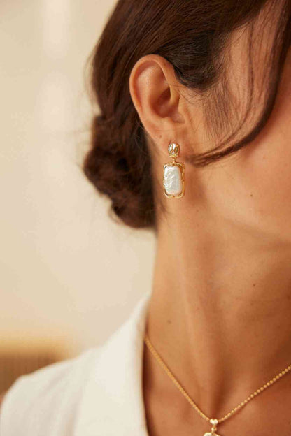 Close-up of gold pearl earring worn