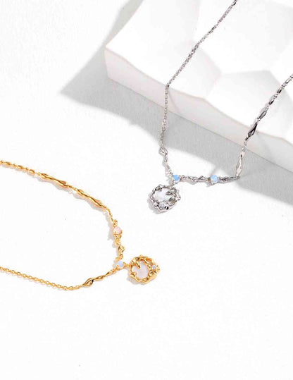 two necklaces sitting next to each other on a white surface