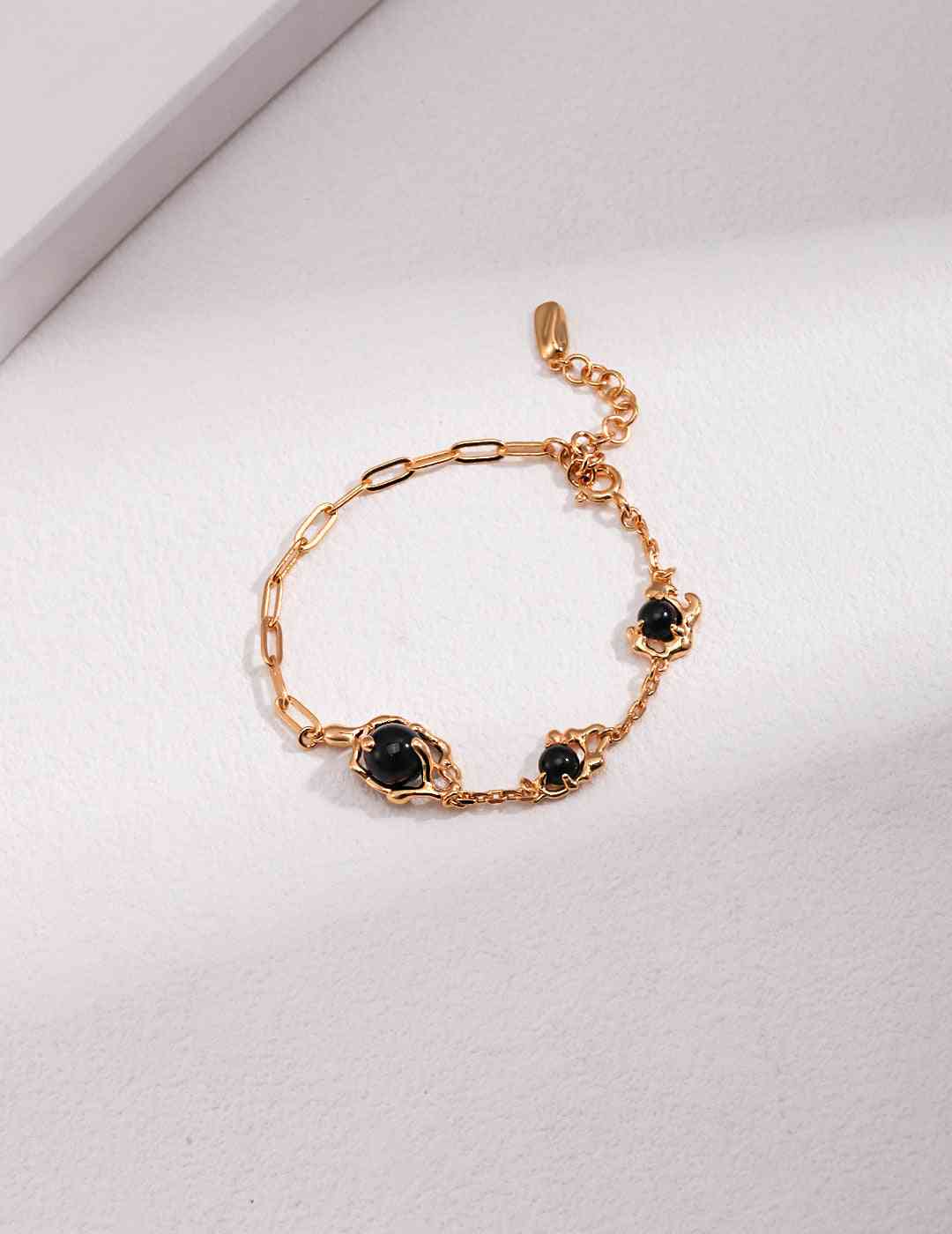a gold chain bracelet with black agate stones