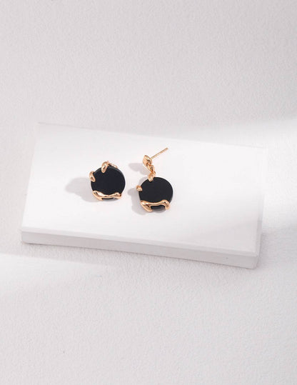 a pair of black agate stone and gold earrings on a white surface