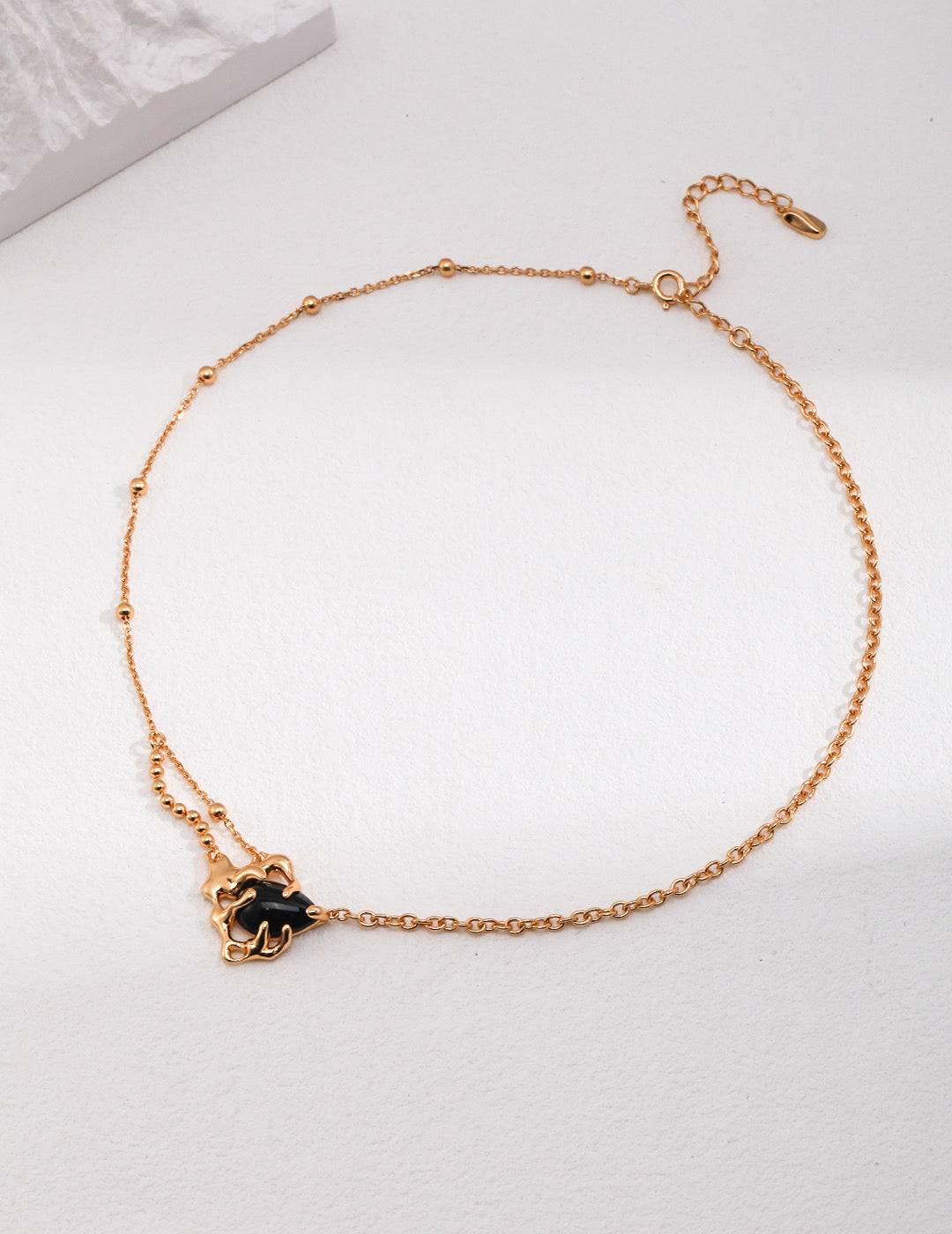 a gold chain bracelet with a black flower charm