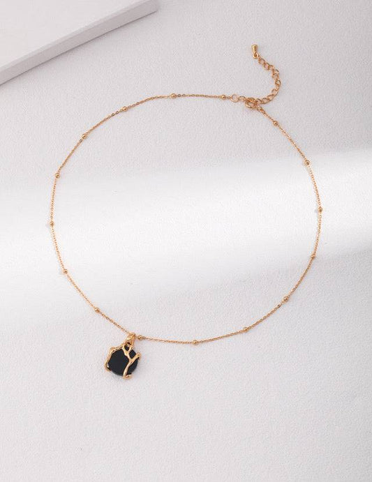 a gold chain bracelet with a black agate stone pendant