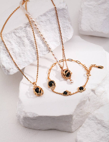 a set of gold chains with black agate stone