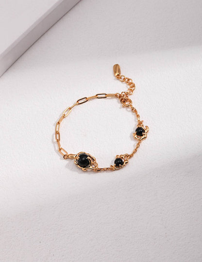 a gold chain bracelet with black agate stones