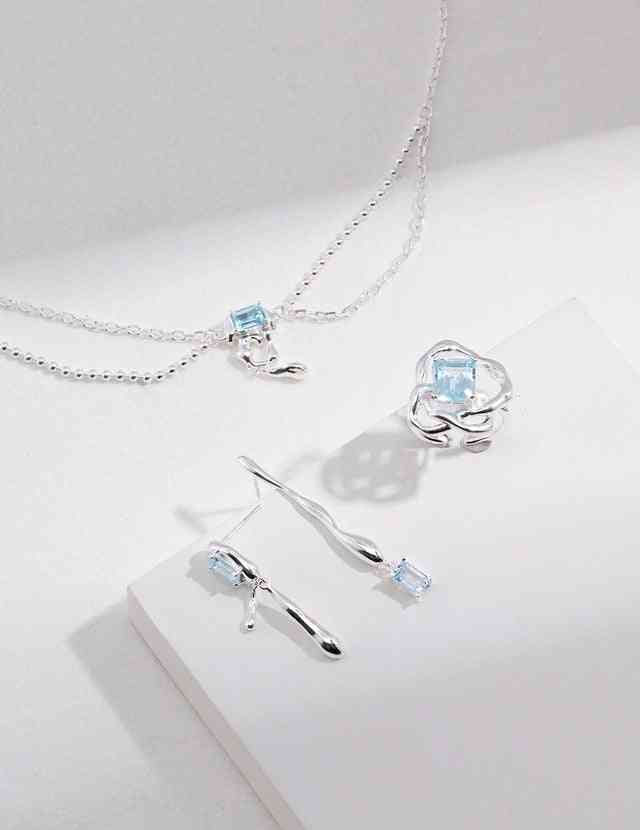 a pair of blue topaz earrings and a blue topaz necklace on a white surface