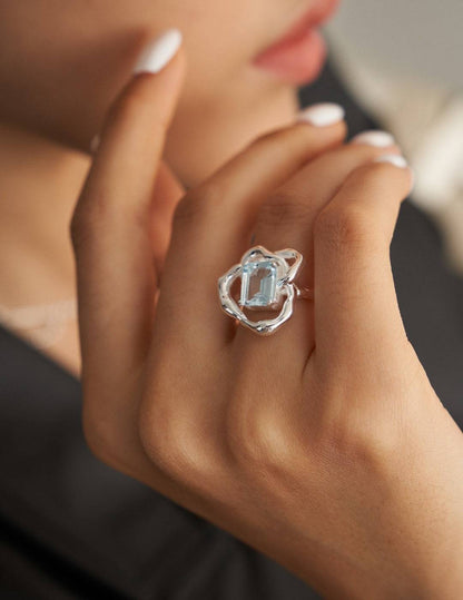 a close up of a person wearing a blue topaz ring