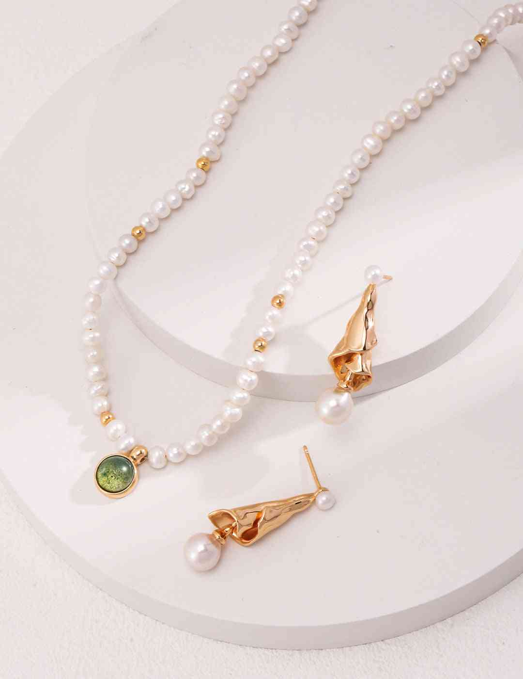 three necklaces with pearls and a green stone