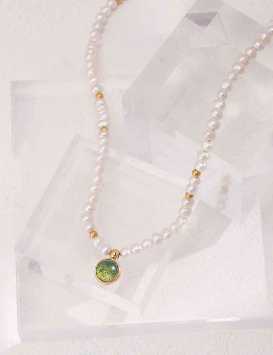 a white pearl necklace with a green aquatic agate stone
