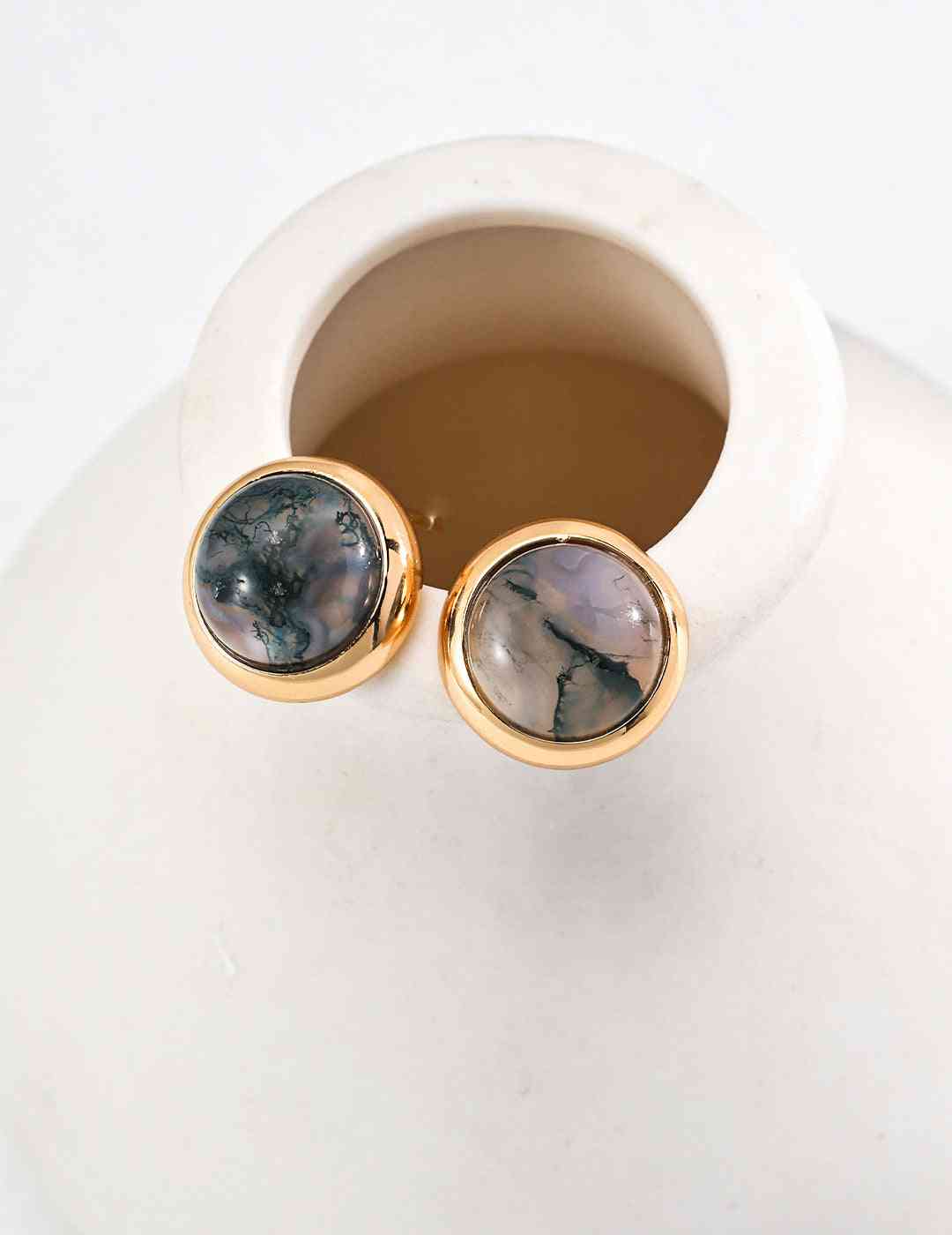 a close up of a pair of aquatic agate stone earrings on a vase