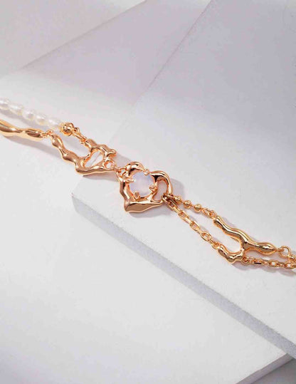 a close up of a gold bracelet with opal stone on a white surface