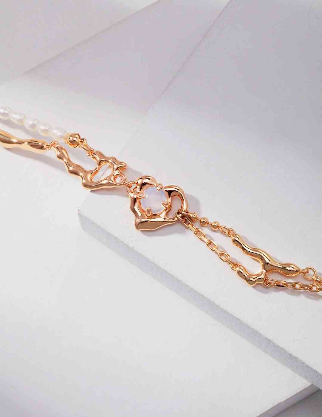 a close up of a gold bracelet with opal stone and pearls
