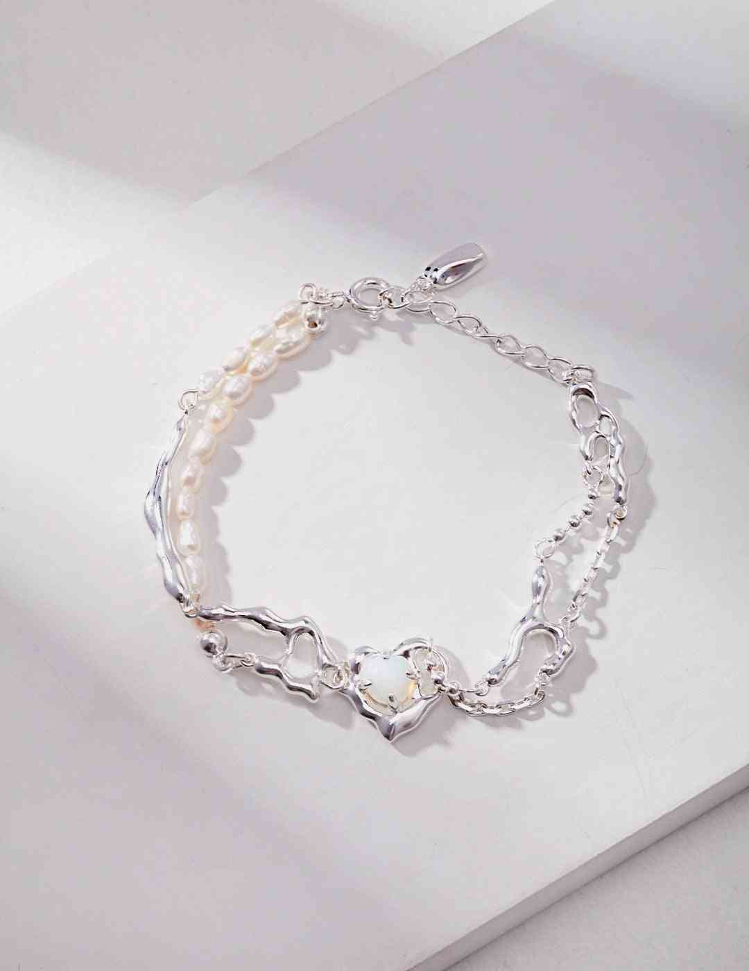 a silver bracelet with pearls and a heart charm