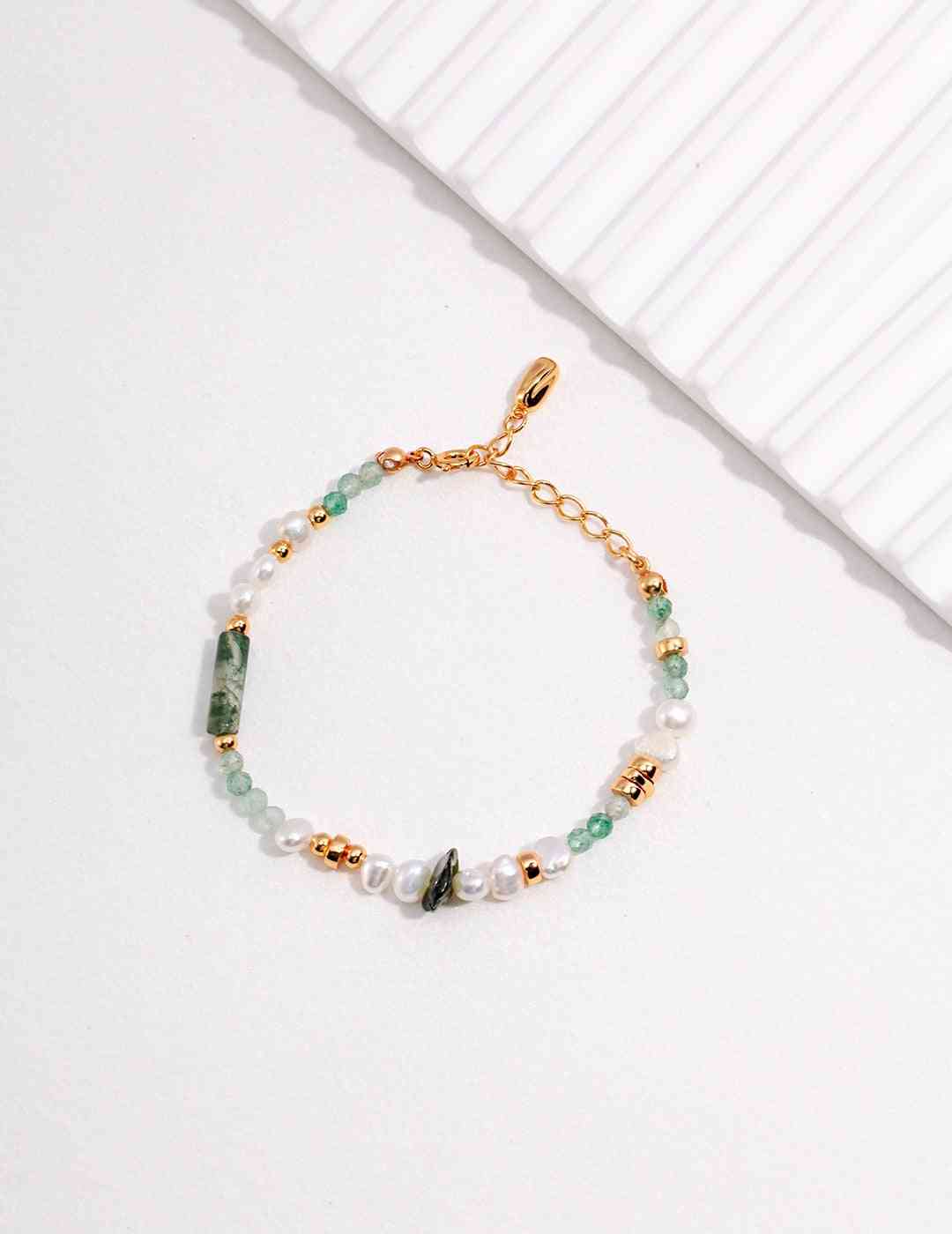 a gold chain bracelet with green and white beads