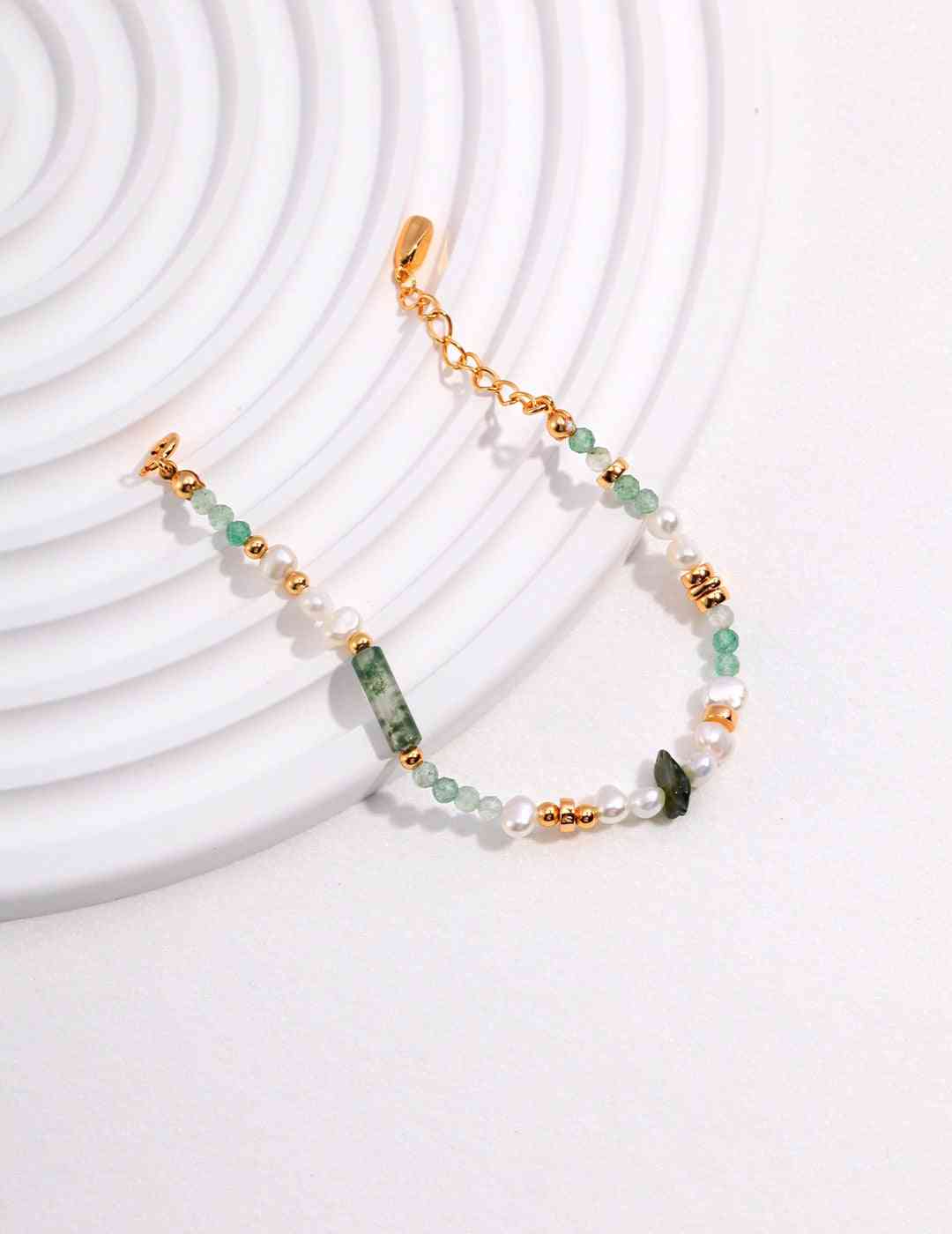 a green dongling jade and aquatic agate bracelet on a white plate