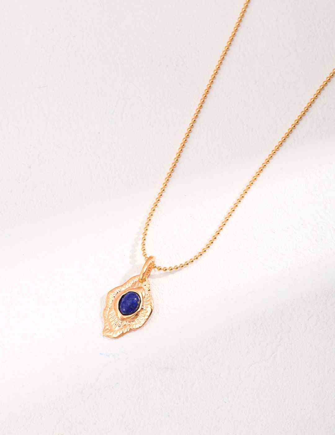 a gold necklace with a blue lapis lazuli stone on it