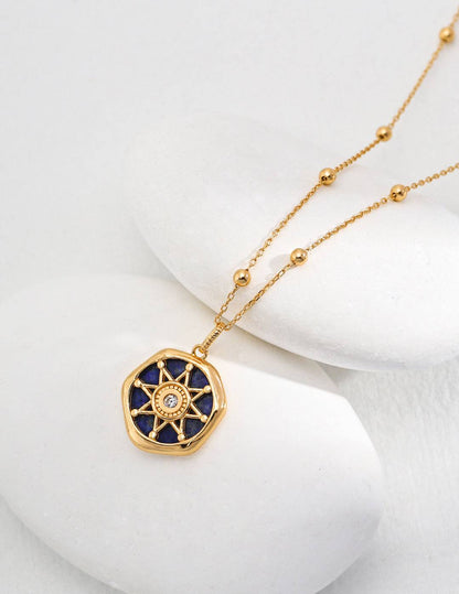 a gold necklace with a blue lapis lazuli stone in the center