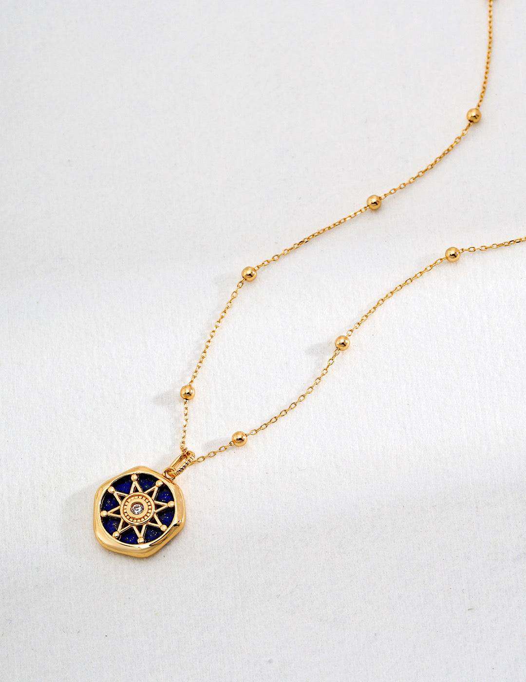 a gold necklace with a blue and white pendant