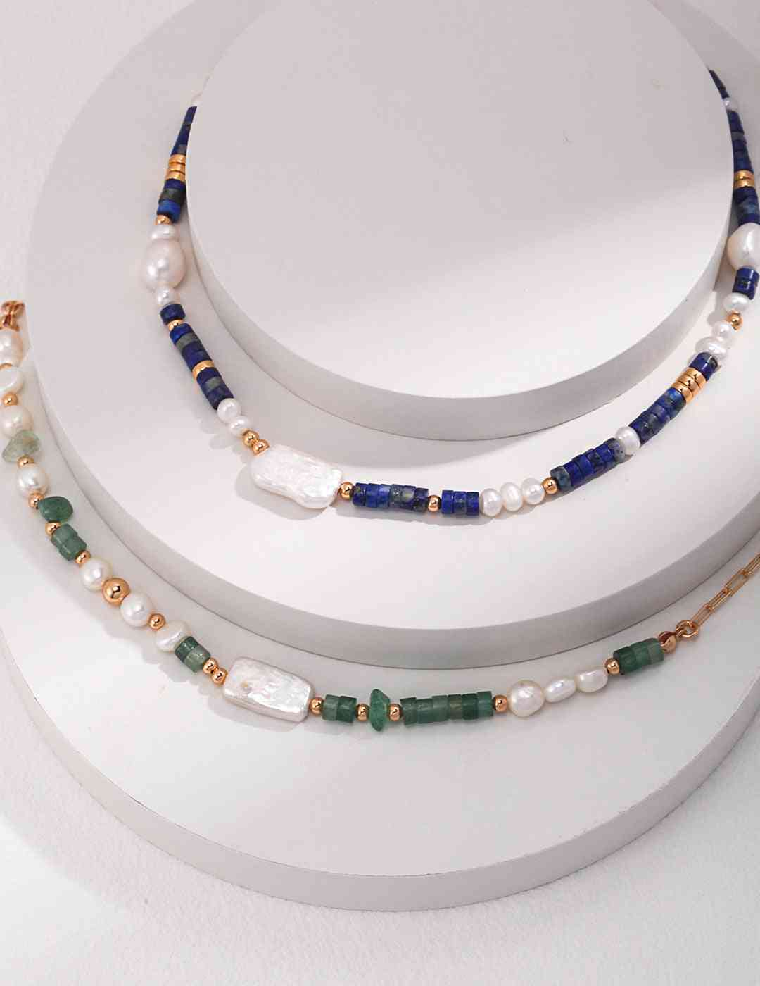 three necklaces of different colors on a white surface