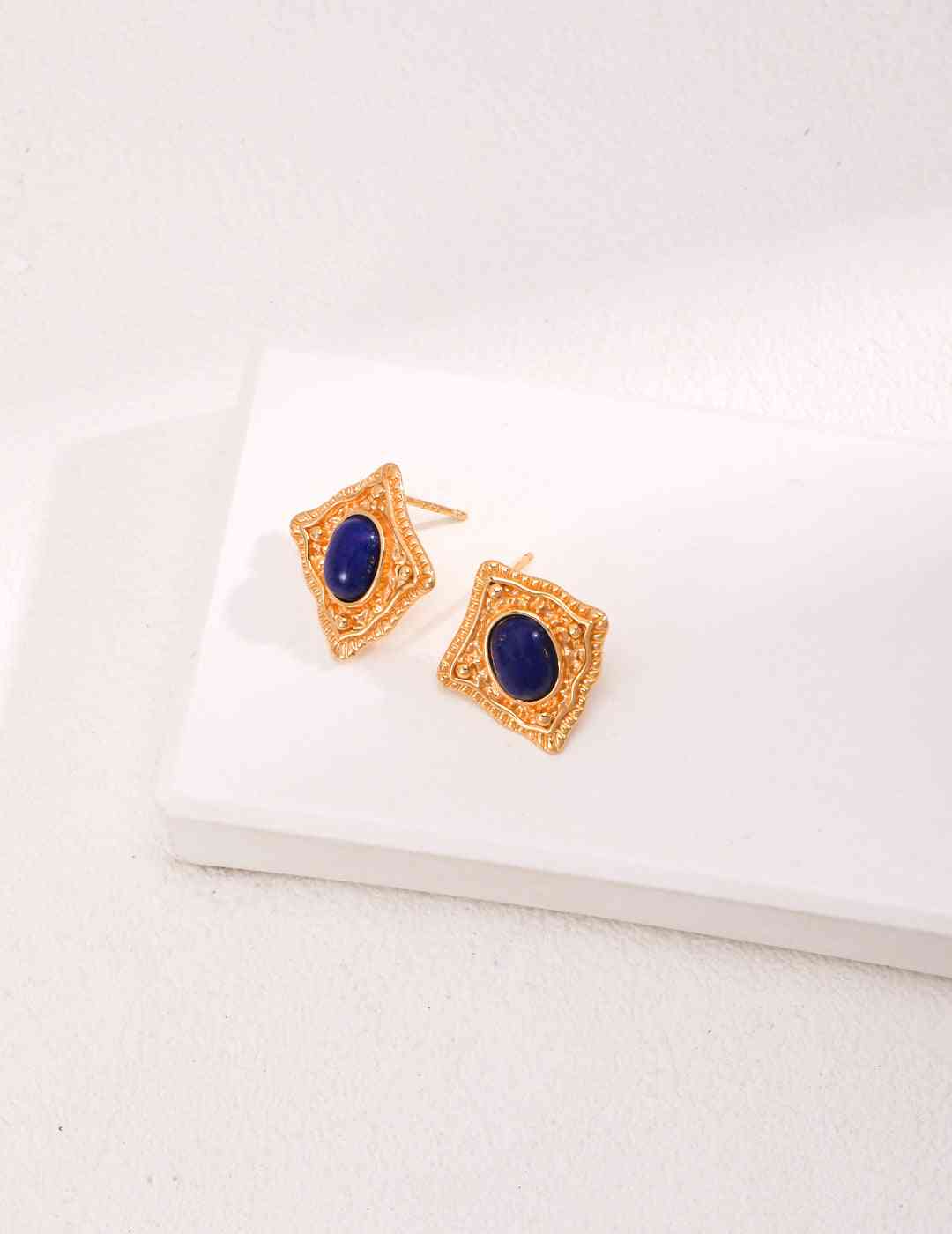 a pair of gold earrings with a blue stone