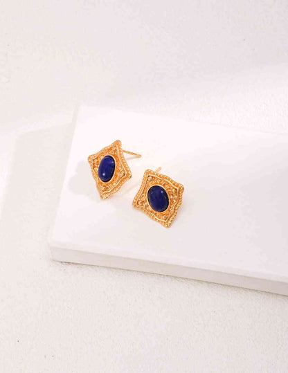 a pair of gold earrings with a blue stone