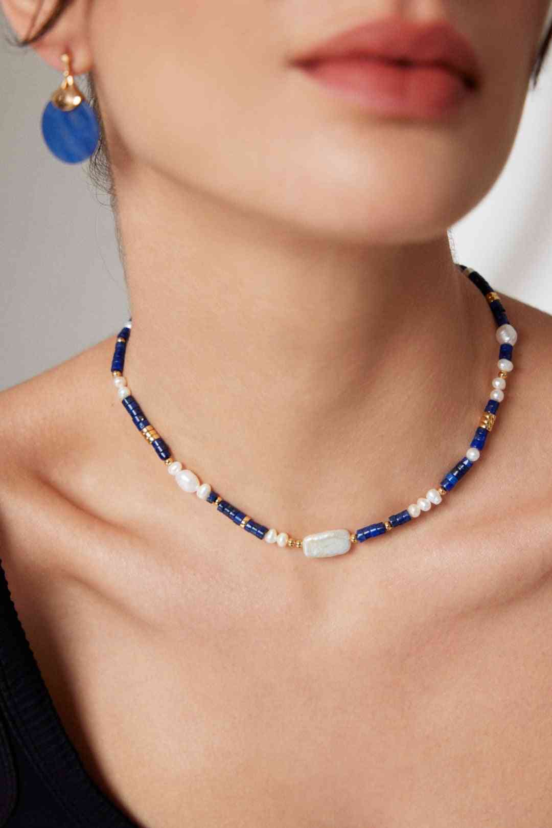 a woman wearing a blue and white necklace