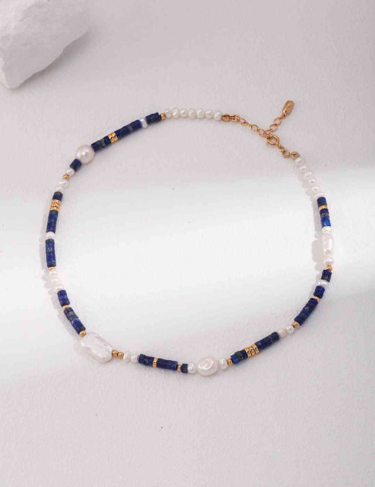 a blue and white beaded necklace on a white surface
