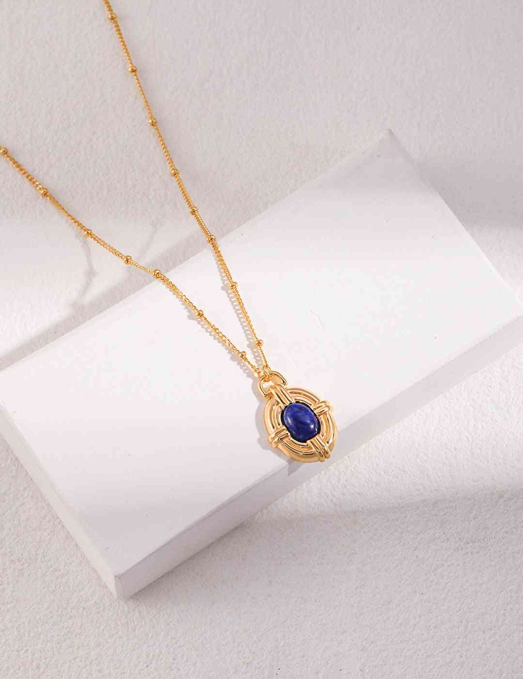 a gold necklace with a blue stone on it