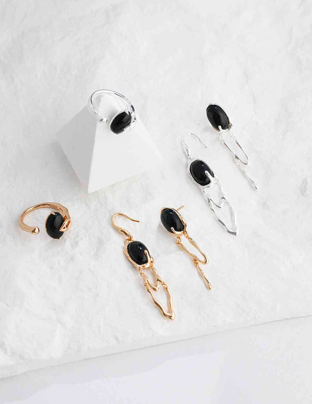 five pairs of earrings on a white surface