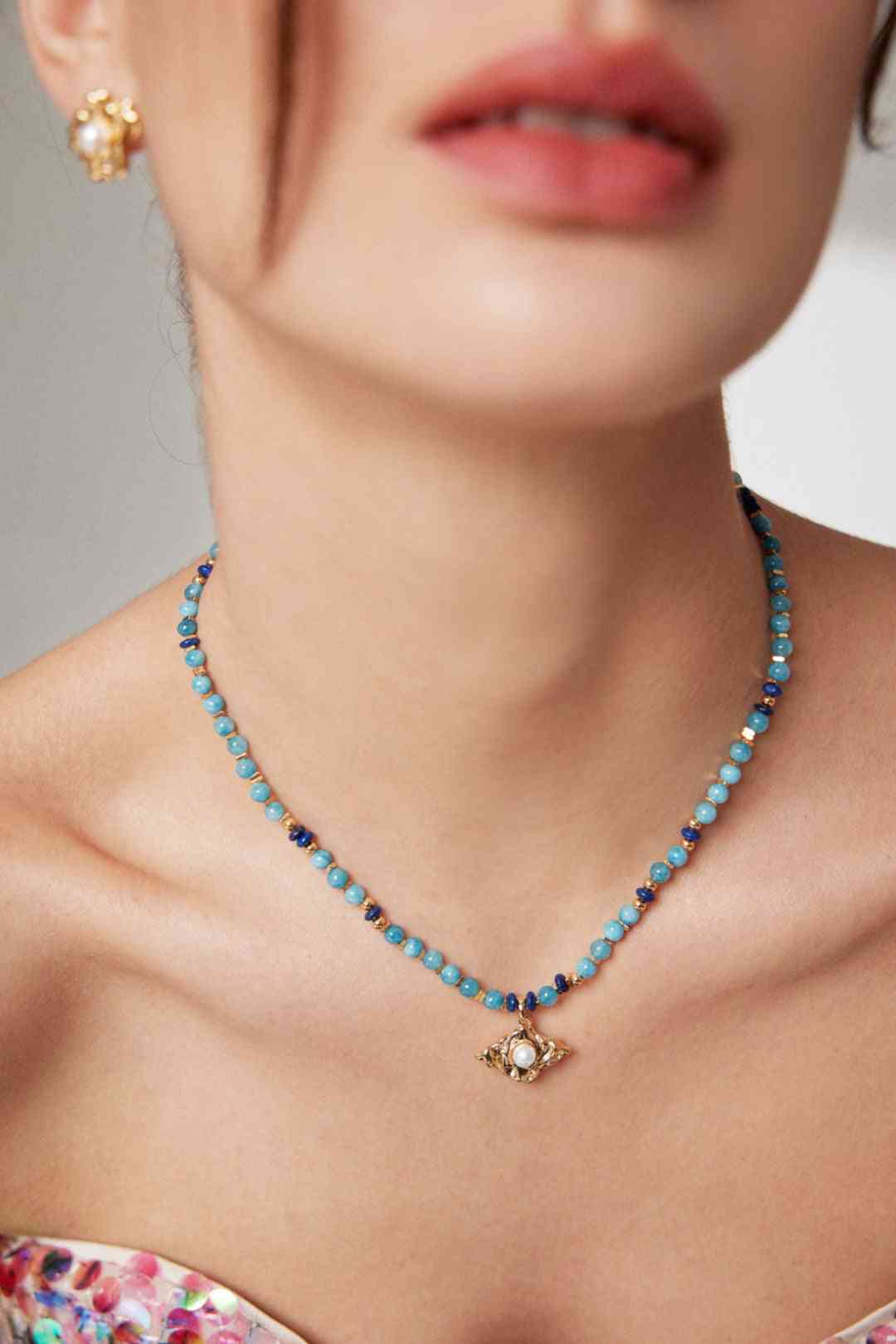 a close up of a woman wearing a amazonite necklace