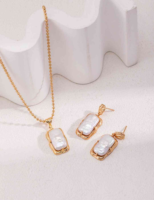 Gold pearl necklace and earrings set on white background