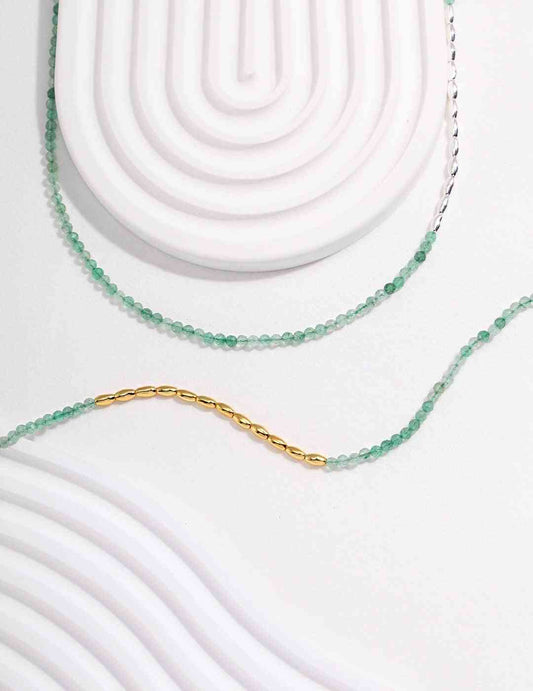 a green dongling jade beaded necklace on a white surface