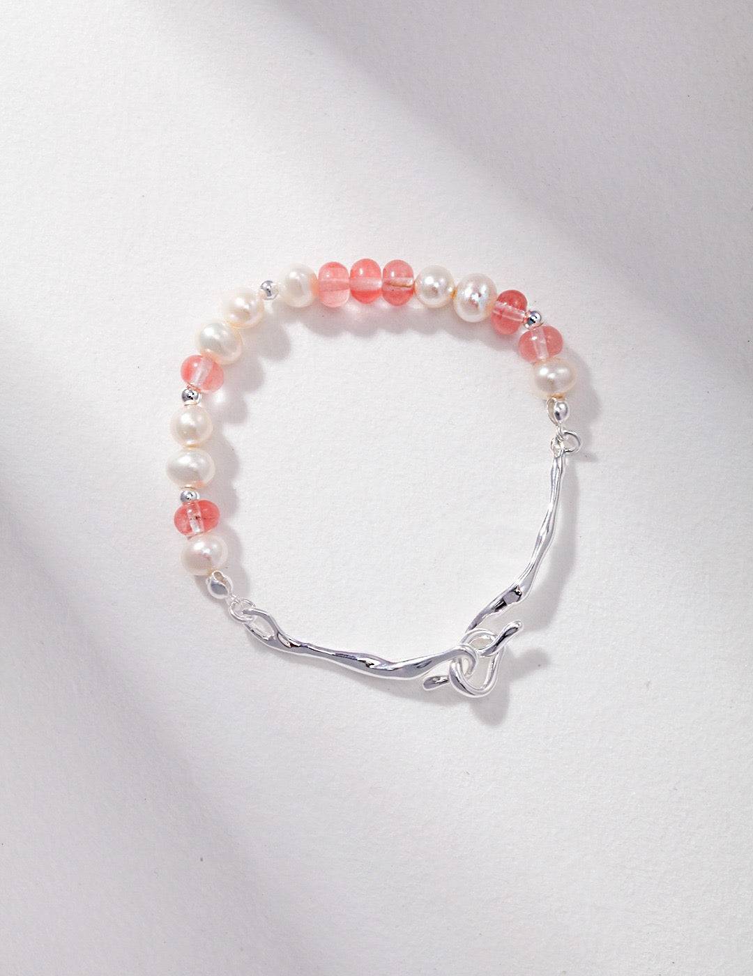 a close up of a strawberry quartz bracelet on a white surface