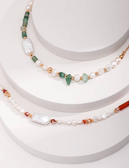 three necklaces of different colors and shapes on a white surface