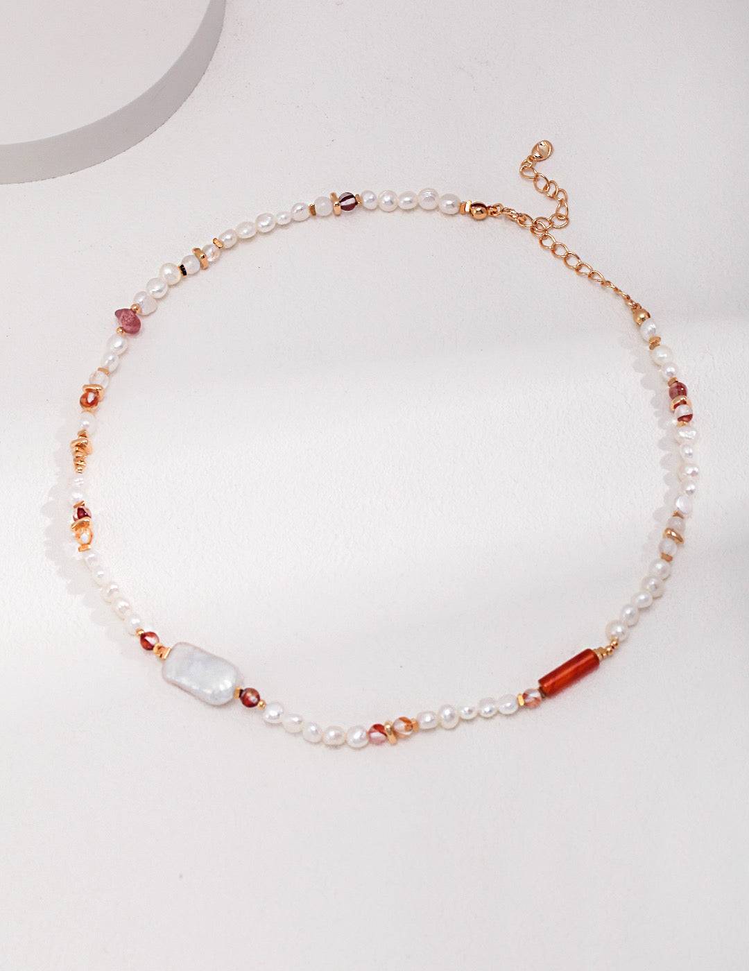 a white necklace with a red and white bead