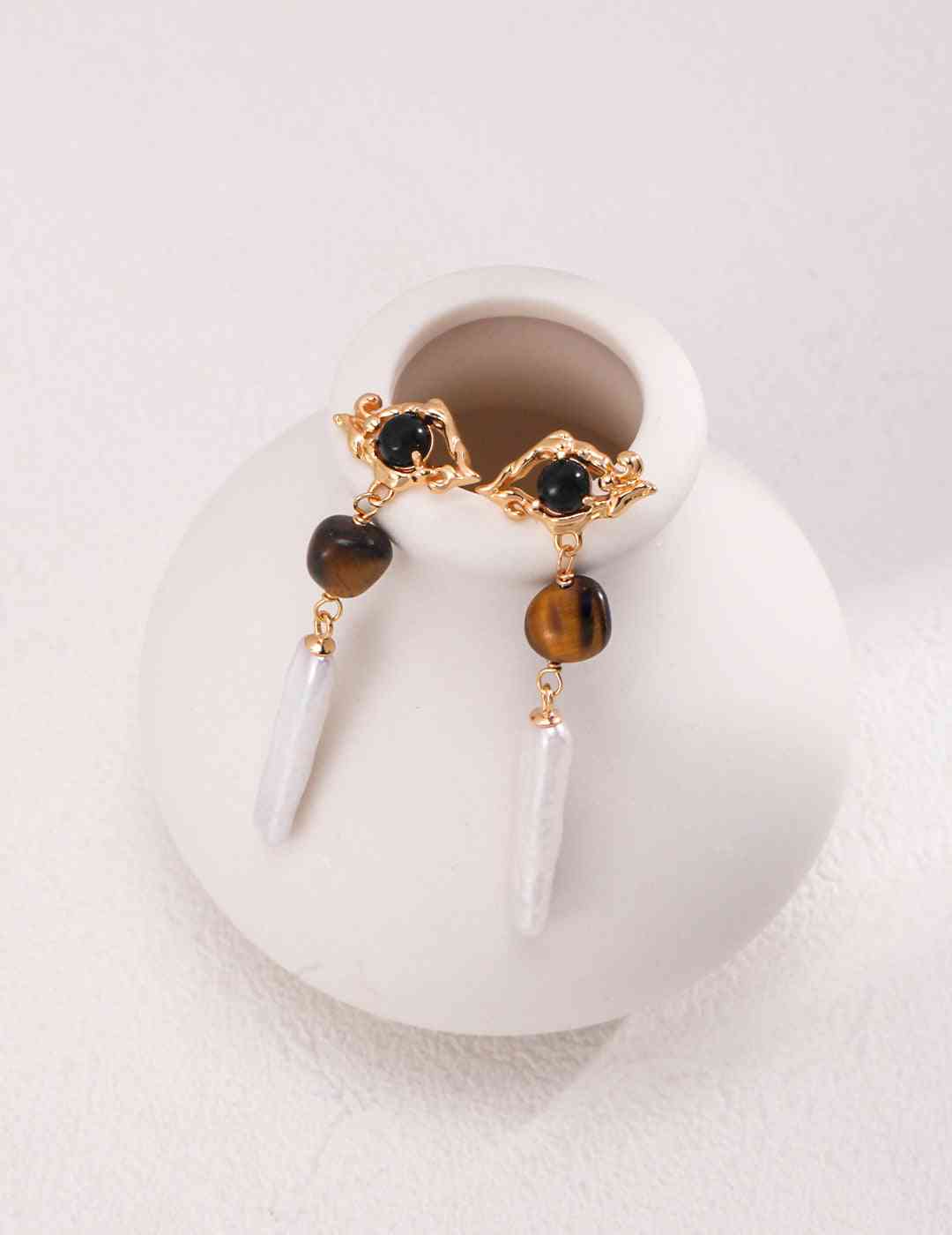 a pair of earrings sitting on top of a white vase