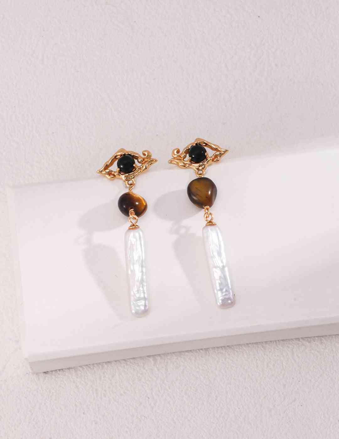 a pair of tiger's eye earrings on a white surface