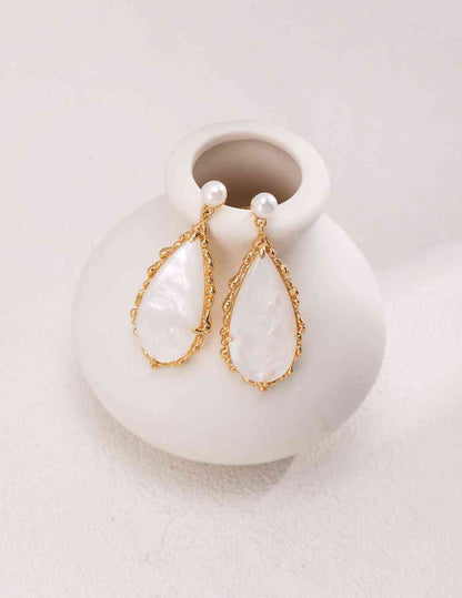 a white vase with a pair of earrings on it