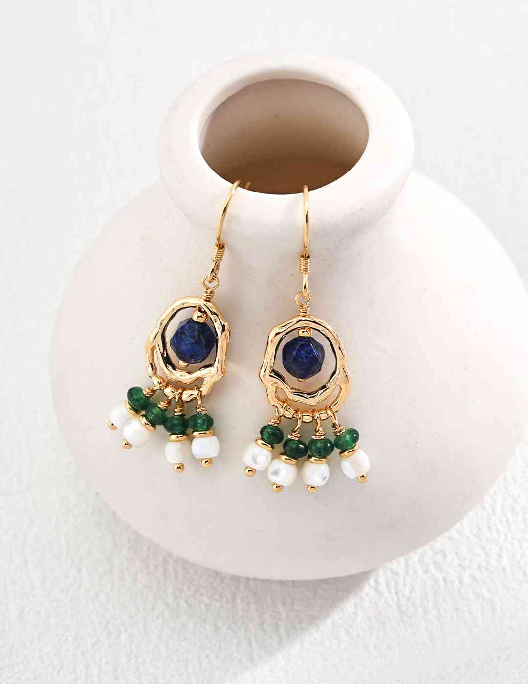 a pair of lapis lazuri earrings sitting on top of a white vase