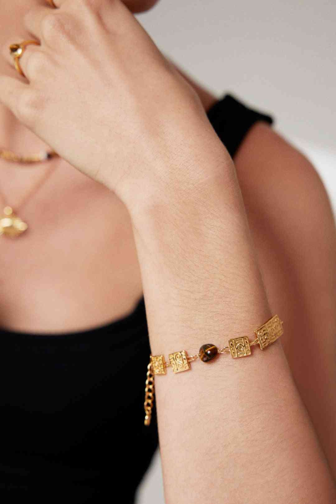 a woman wearing a gold bracelet and a black top