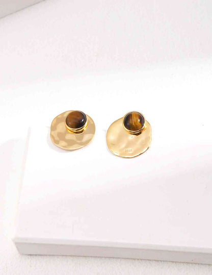 a pair of tiger's eye stone earrings sitting on top of a white surface