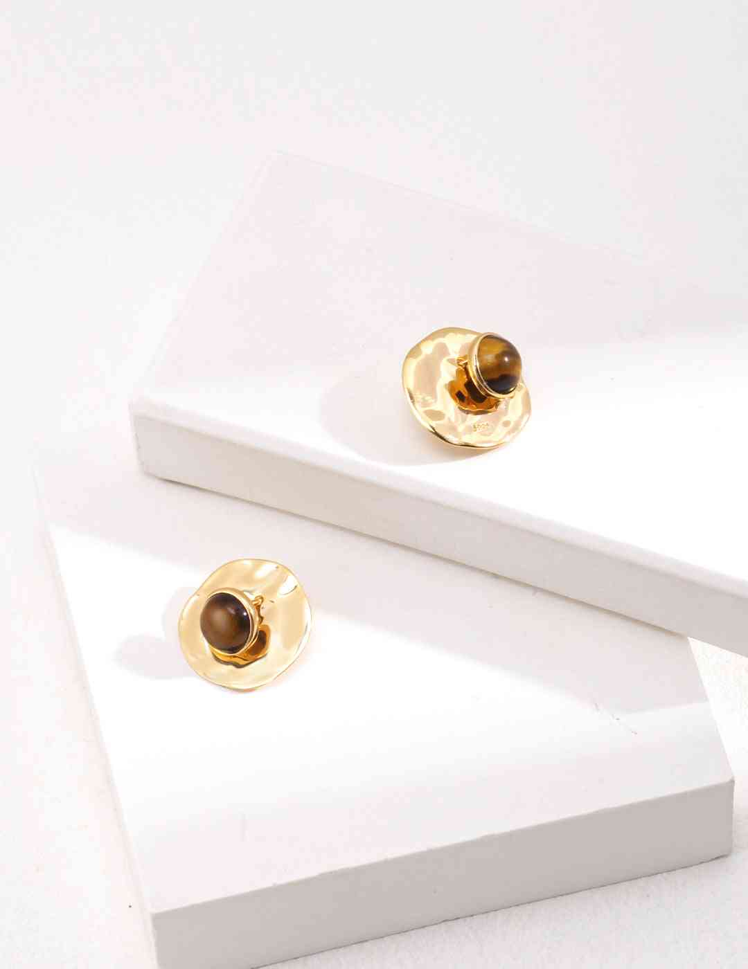 a pair of tiger's eye stone earrings sitting on top of a white surface