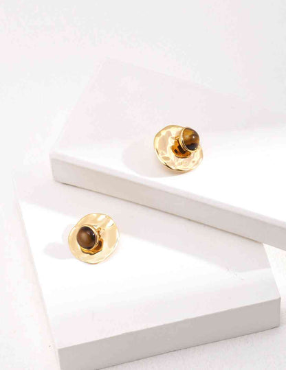 a pair of tiger's eye stone earrings sitting on top of a white surface