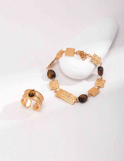 a pair of tiger's eye stone bracelets and a tiger's eye stone ring on a white surface