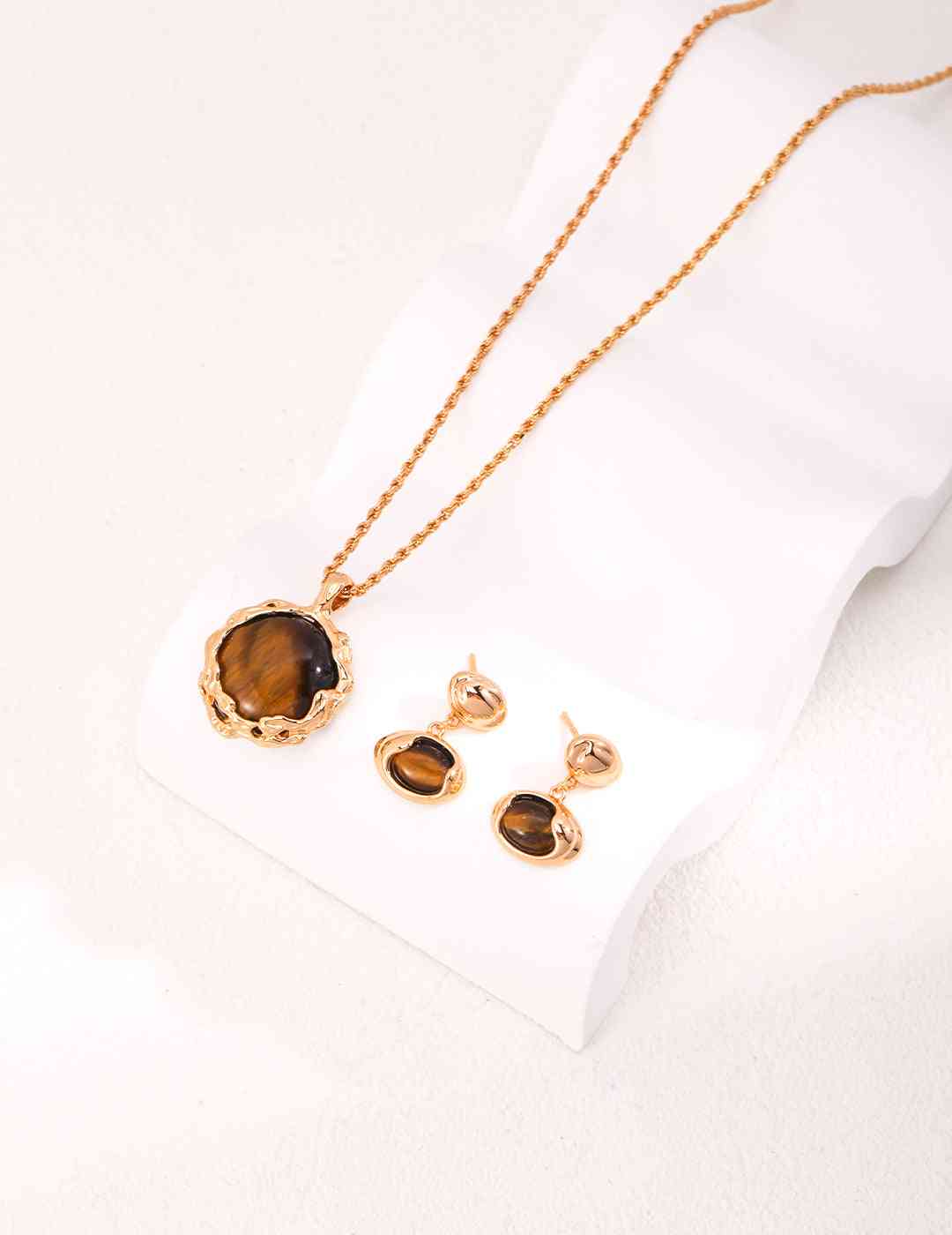 a tiger's eye stone necklace and earring set on a white surface