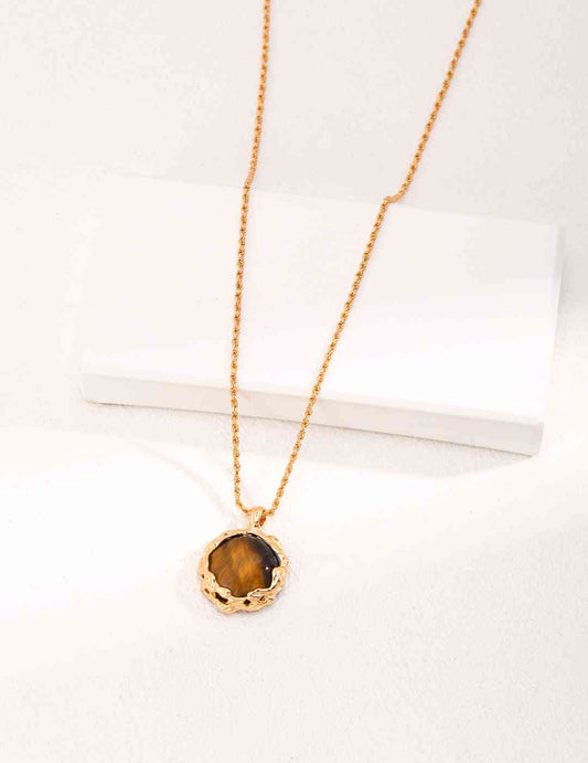 a gold necklace with a tiger's eye pendant