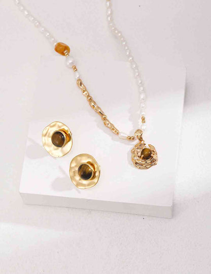 a necklace and earrings with tiger's eye stone on a white surface