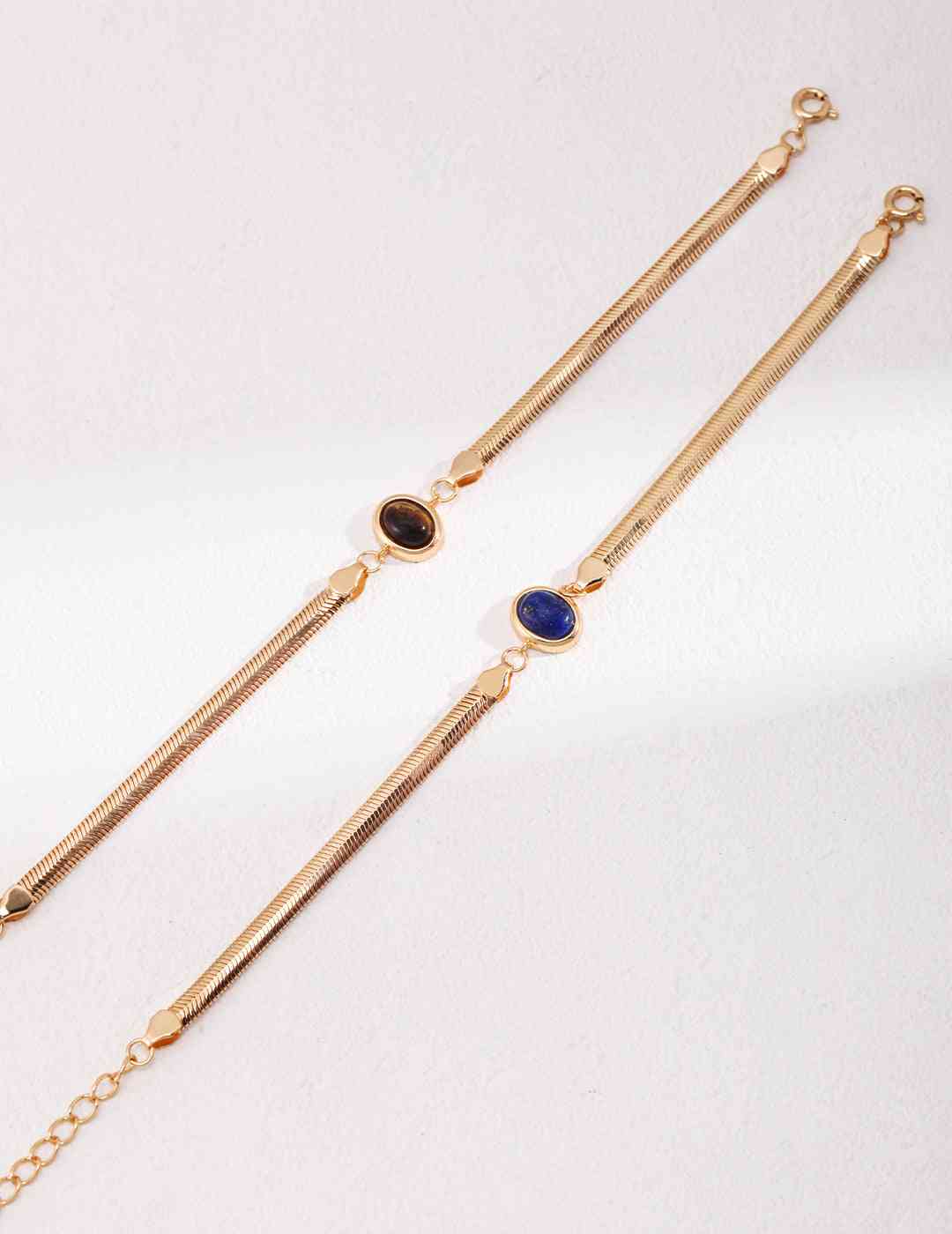 a pair of gold chain bracelets with blue or brown stones