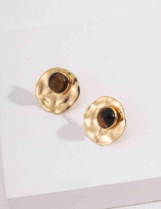 a pair of gold earrings with a tiger's eye stone